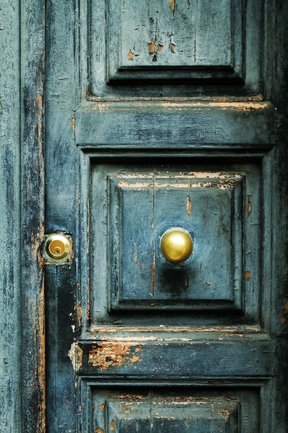Closeup of blue turquoise old textured antique door with gold br
