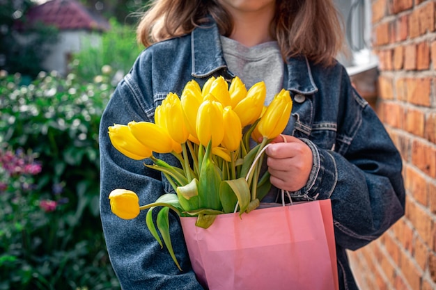 Primo piano un mazzo di tulipani gialli nelle mani di una bambina