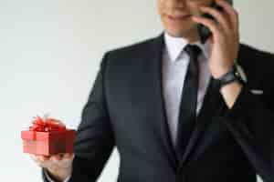 Free photo closeup of business man holding gift box and talking on phone