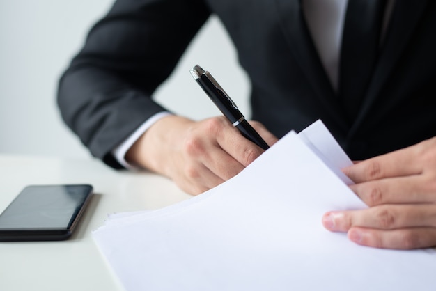 Closeup of business man signing document at office desk