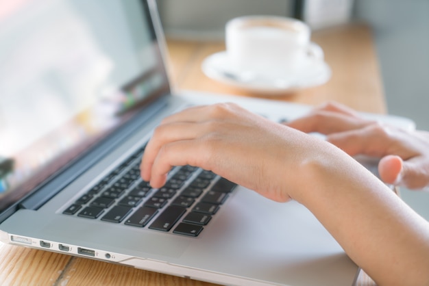 Primo piano di donna d'affari mano digitando sulla tastiera del computer portatile