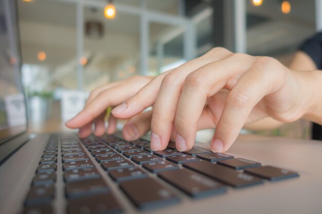 Closeup of business woman hand typing on laptop keyboard .