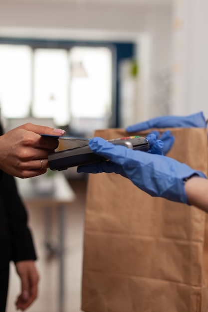 Closeup of businesswoman paying takeaway food order with credit card using POS contactless service during takeout lunchtime