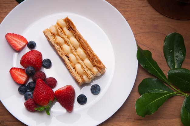 Крупным планом порции торта и свежие ягоды на тарелке на столе