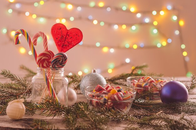 Closeup of candies in bowls on the table decorated with Christmas ornaments