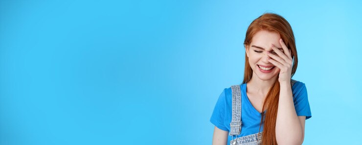 Бесплатный Фотография крупным планом беззаботная веселая симпатичная рыжая женщина смеется, краснея, мило искренне хихикает, наклоняет голову