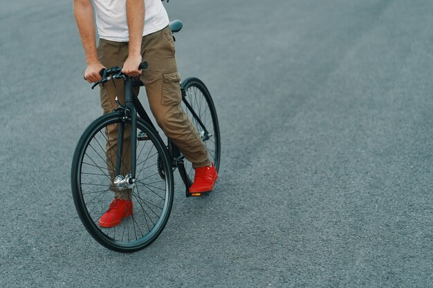 都市道路で古典的な自転車に乗ってカジュアルな男の足のクローズアップ