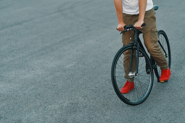 Closeup of casual man legs riding classic bike on city road