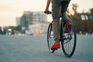 Primo piano delle gambe casuali dell'uomo che guidano bici classica sulla strada di città