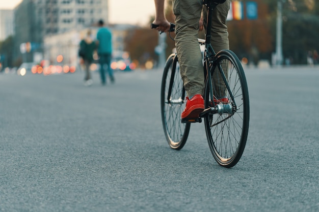 都市道路で古典的な自転車に乗ってカジュアルな男の足のクローズアップ