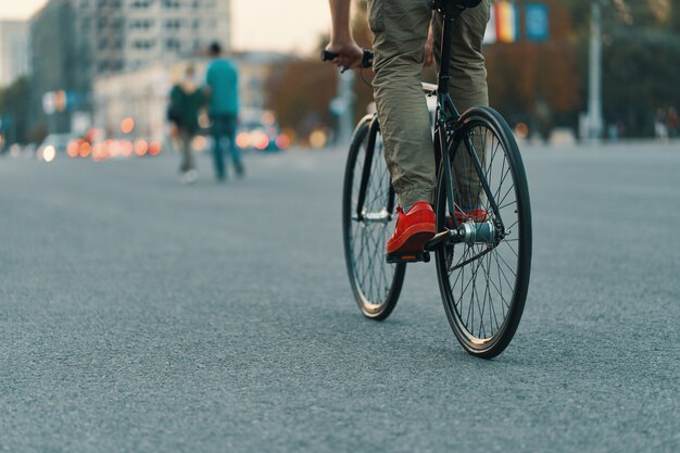 Крупным планом случайные ноги человека, езда классический велосипед на городской дороге