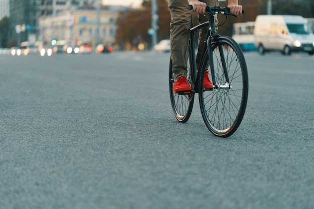 Foto gratuita primo piano delle gambe casuali dell'uomo che guidano bici classica sulla strada di città