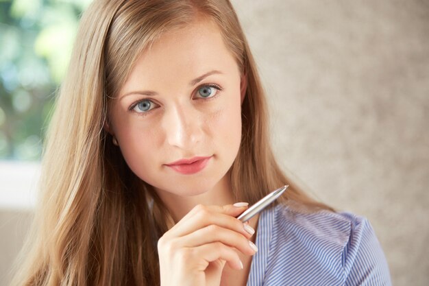 Closeup of Caucasian woman looking at camera holding pen