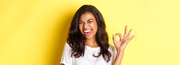 Free photo closeup of cheerful africanamerican female model showing okay sign winking and looking satisfied rec