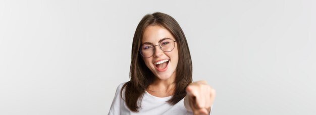 Closeup of cheerful beautiful girl in glasses smiling poiting finger at camera