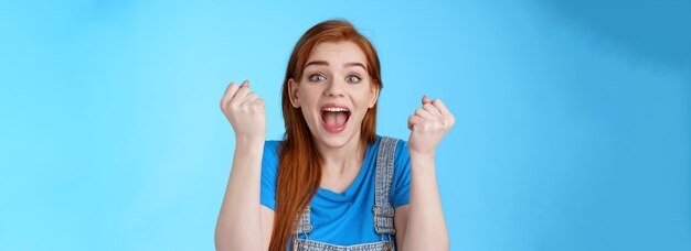 Free photo closeup cheerful lucky redhead woman win lottery fist pump yell yeah hooray winning bet smiling glad