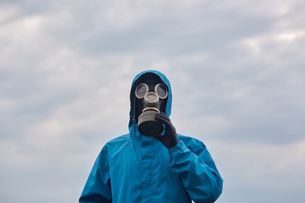 屋外でポーズをとるクローズアップ化学科学者または生態学者、青い制服と防毒マスクを身に着け、科学者は周囲を探検し、私たちの環境を保護することを求めます。生態学の概念。