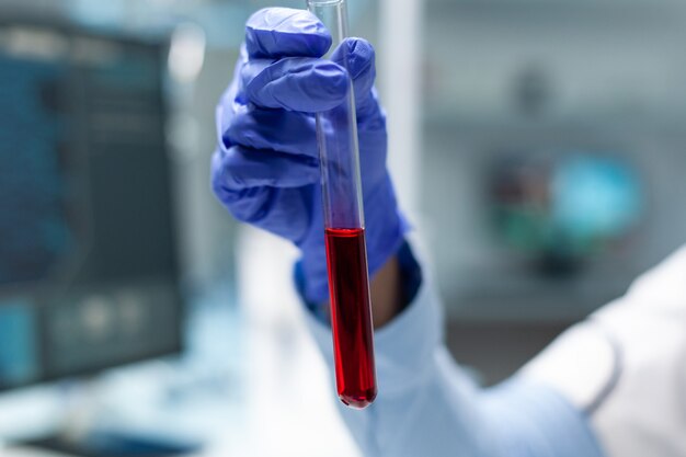Closeup of chemist researcher holding transparent test tube with blood