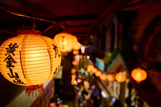 Closeup of Chinese paper lantern with lights surrounded by buildings