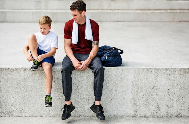 Free photo closeup of coach sitting on step with young boy tying trainers robe