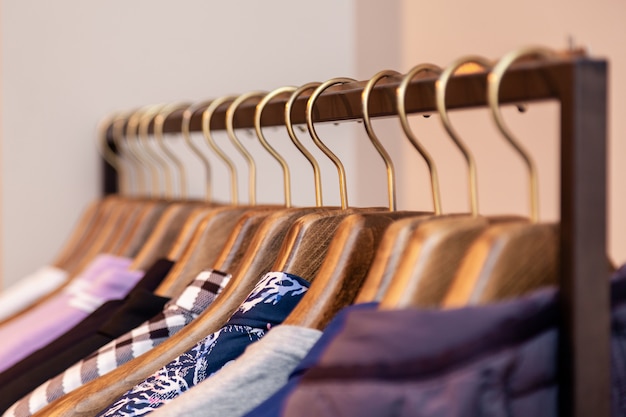 クローズアップカラフルな男性 女性の服をハンガーに掛かっているブティックで服 金属製のスタンドのラック 高級店 ショッピングモール 店舗の販売 小売店 セカンドハンドアウトレットを開くコンセプト プレミアム写真