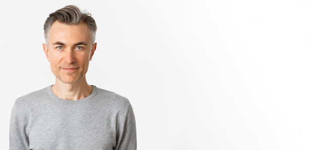 Closeup of confident handsome middleaged man with short gray hairstyle smiling and looking determine