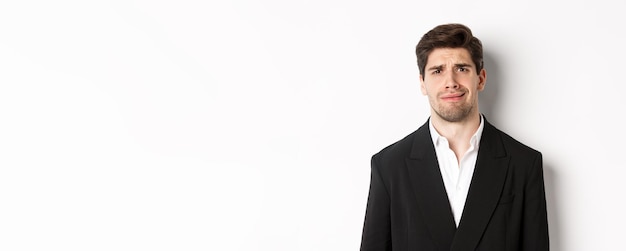 Closeup of confused handsome man in suit grimacing and looking perplexed wearing trendy suit standin