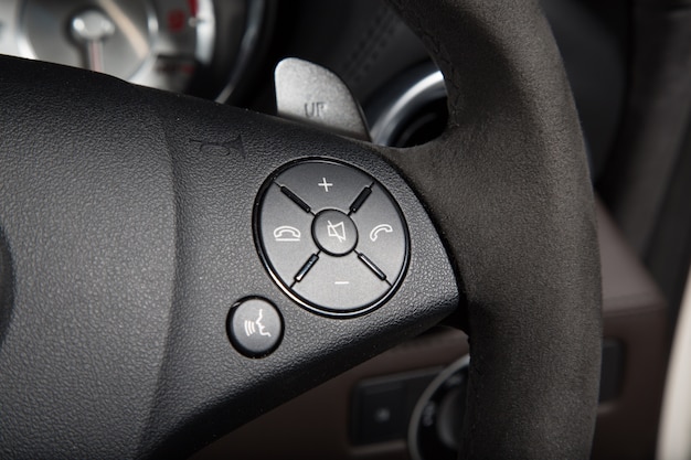 Free photo closeup of control buttons on the steering wheel of a luxury car under the lights