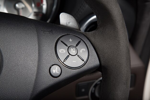 Closeup of control buttons on the steering wheel of a luxury car under the lights