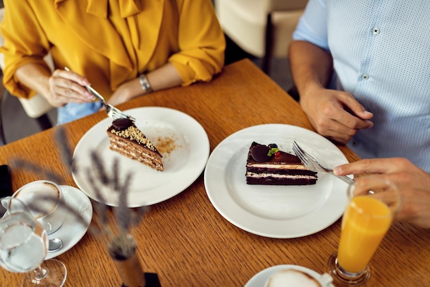 カフェでデザートのケーキのスライスを持っているカップルのクローズアップ