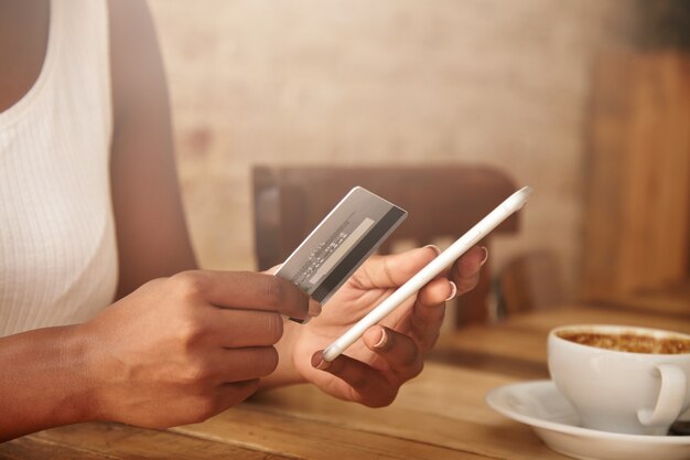 Closeup of credit card and smartphone in woman's hands