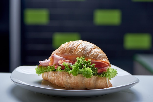 Closeup of croissant with greens ham and vegetables in pub