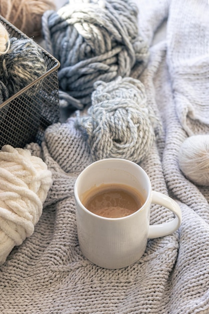Free photo closeup cup of coffee knitted element and yarn threads