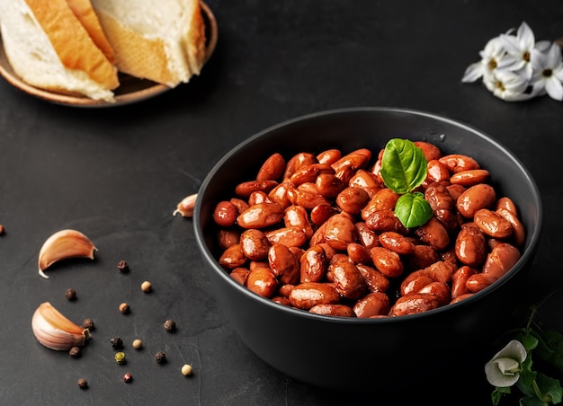 Closeup of a cup with boiled red beans decorated with basil leaves