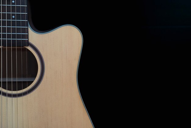 Closeup of cutaway acoustic guitar over black background