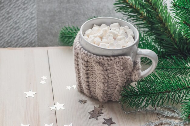 Closeup of a cute mug full of marshmallows surrounded by Christmas decorations on the table