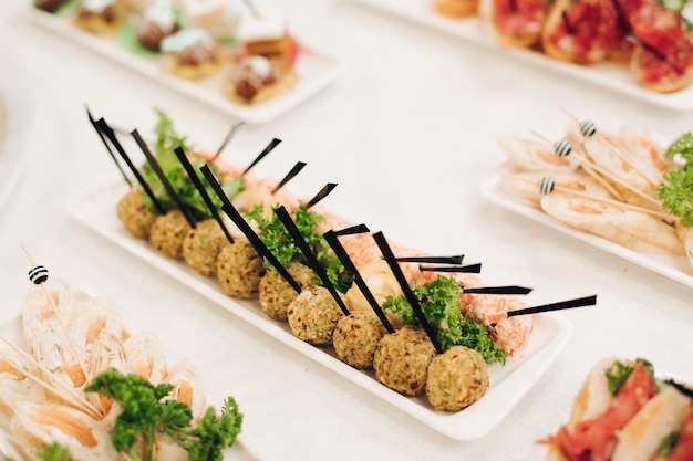 Foto gratuita primo piano di deliziose polpette di carne e involtini di pesce serviti su palline rettangolari con bastoncini per spuntini varietà di cibo per feste aziendali di compleanno o feste di matrimonio