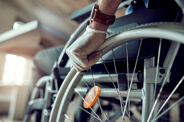 Closeup of disabled businessman wearing protective gloves while pushing himself in a wheelchair