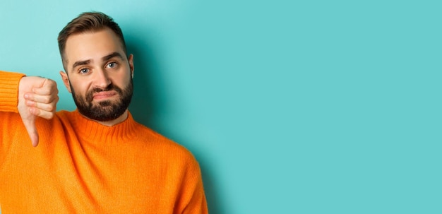 Free photo closeup of disappointed caucasian man with beard showing thumb down and grimacing displesed negative