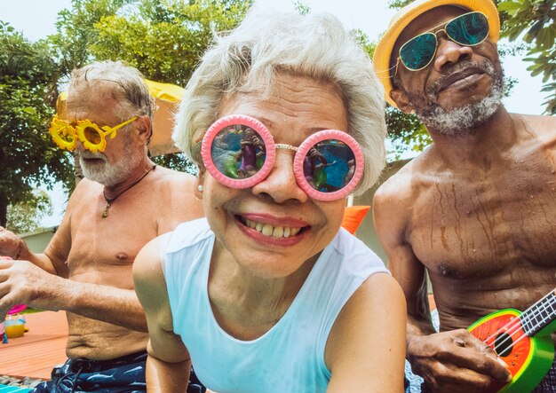 Closeup of diverse senior adults sitting by the pool enjoying summer together