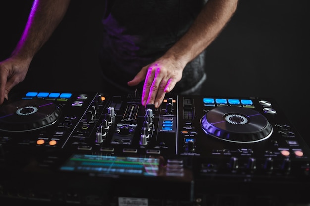 Closeup of a DJ working under the colorful lights in a studio