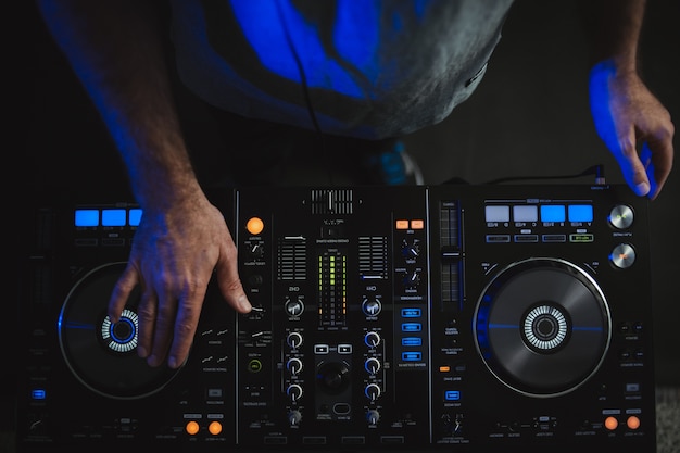 Free photo closeup of a dj working under the colourful lights in a studio