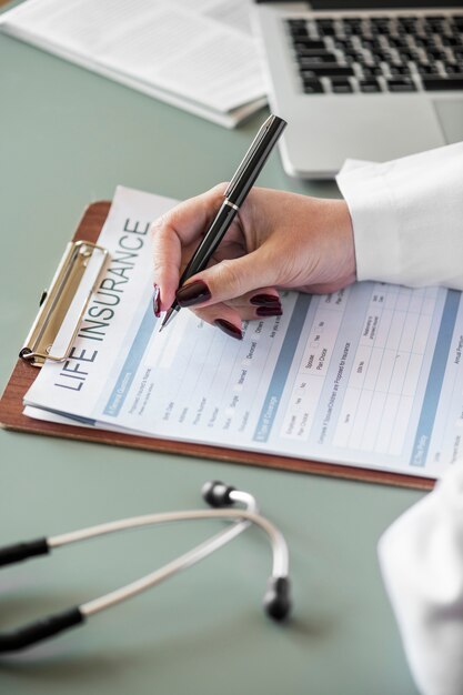 Closeup of doctor filling life insurance form