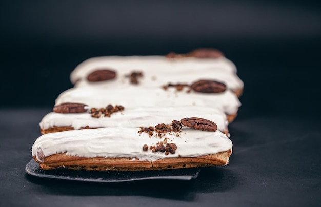 Closeup of eclairs in white glaze with pecans