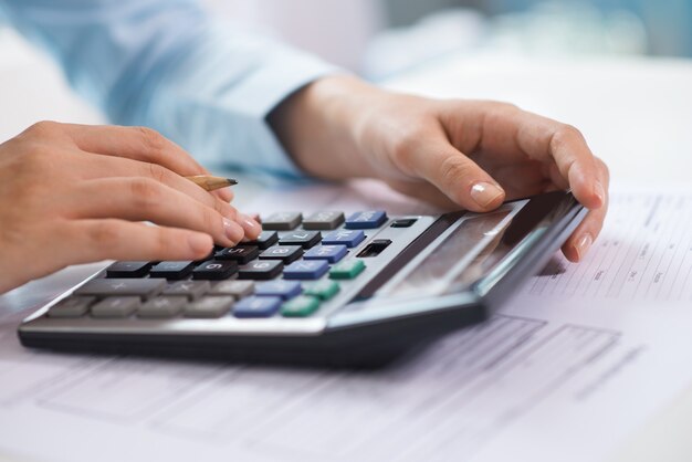 Closeup of economist working and counting data on calculator