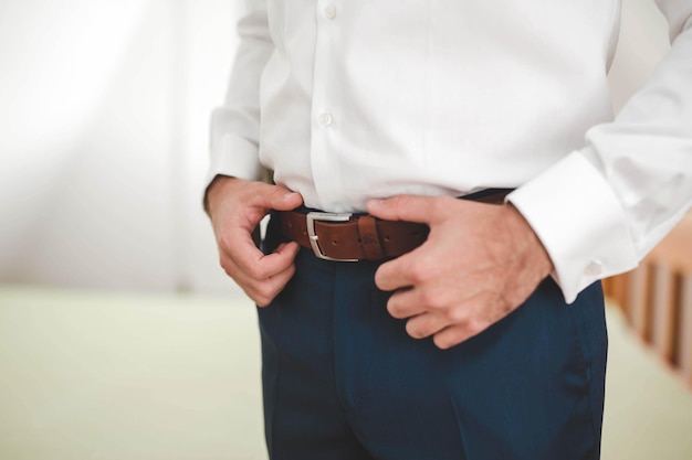 Free photo closeup of an elegant  man standing with his hands on his leather belt on the trousers