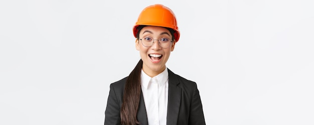 スーツと安全ヘルムで興奮した明るいアジアの女性チーフ建設エンジニア建築家のクローズアップ