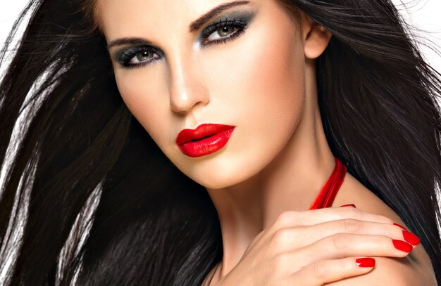 Closeup face of a beautiful brunette woman with red nails and lips