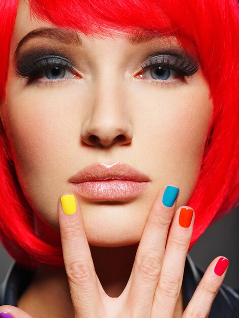 Closeup face of a beautiful  girl with bright multicolor nails.