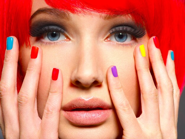 Closeup face of a beautiful girl with bright multicolor nails.